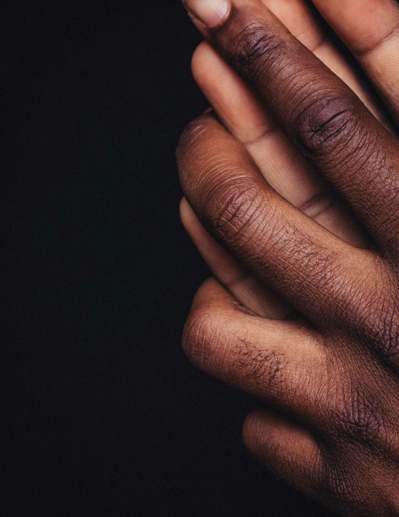 two hands with darker skin, palms towards each other with fingers interlaced and reaching upwards. FAQ about sexological bodywork, consent, embodiment